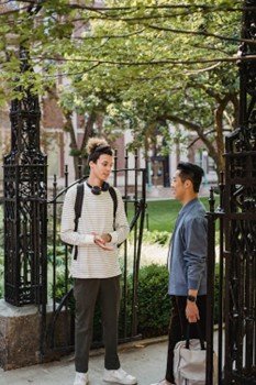 Friends standing on the street discussing near a stylish wrought iron fence and gate.