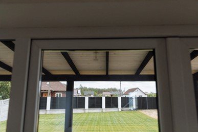 View of a driveway gate and metal fence from a glass window.