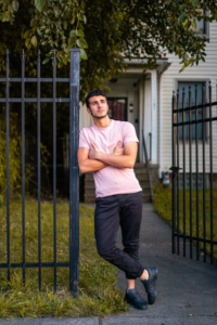 Man posing by a black metal driveway gate.