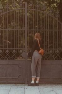 Woman standing in front of a metal driveway gate.