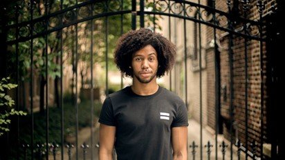 A man standing beside a black wrought iron gate.