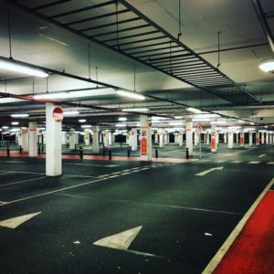 Indoor parking lot with metal fencing and marked parking spaces.