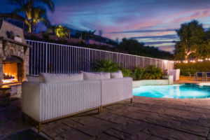 Patio with a pool, deck, and house in the background