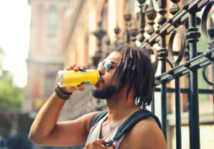 Man drinking with a metal fence visible in the background