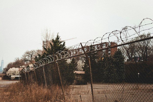 Wide view of a galvanized steel chain link fence along a property line.