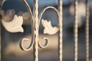 Close-up of a white wrought iron fence showcasing intricate detailing 